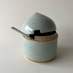 a ceramic container with a spoon in it