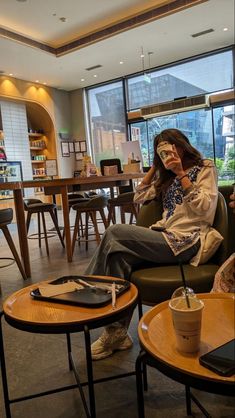 a woman sitting in a chair with her cell phone up to her ear and looking out the window