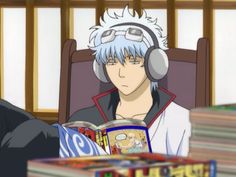 an anime character with headphones on sitting in front of stacks of books and cds