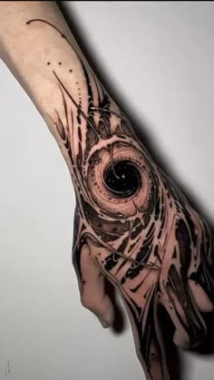 a person's hand with a black and white tattoo design on the left arm