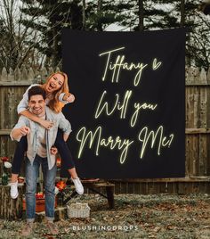 a man holding a woman in front of a sign that says, thank you will you marry me?