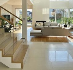 a living room filled with furniture and lots of windows next to a stair case in front of a large window