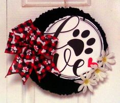 a black and white wreath with a red bow hanging on the front door, decorated with flowers