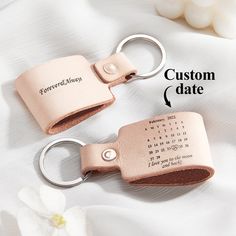 two leather keychains with custom date printed on them, one is pink and the other is brown