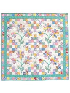 a quilted wall hanging with flowers on the front and side, in pastel colors