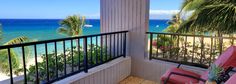 a balcony overlooking the ocean with chairs and palm trees