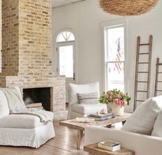 a living room filled with furniture and a fire place in front of a brick wall