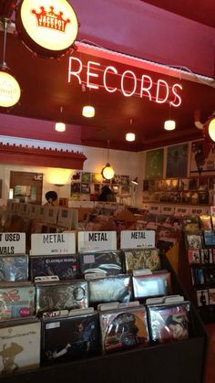 the inside of a record shop with various records on display and neon signs above it