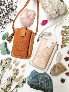 the contents of a purse laid out on a white surface next to rocks and flowers