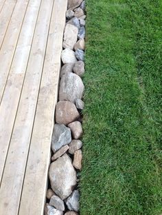 a wooden deck with rocks and grass next to it