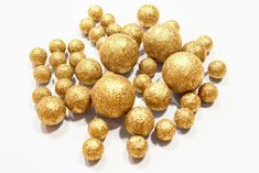 gold glittered balls are scattered on a white surface, as if they were made out of chocolate