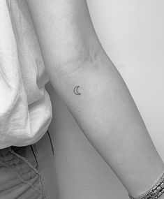 a woman's arm with a small crescent tattoo on the left side of her arm