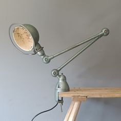 a desk lamp that is on top of a wooden table next to a shelf and wall