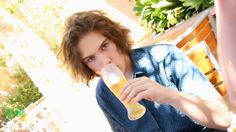 a woman sitting on a wooden bench drinking from a bottle