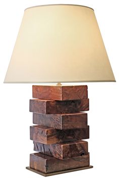 a lamp made out of wooden blocks with a white shade on it's side