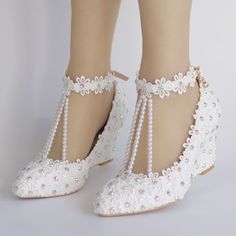 a pair of white high heel shoes with pearls on the ankle straps and lace trimmings