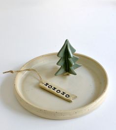 a ceramic plate with a small christmas tree on it and a tag that says toto