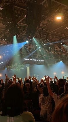 a large group of people standing on top of a stage with their hands in the air