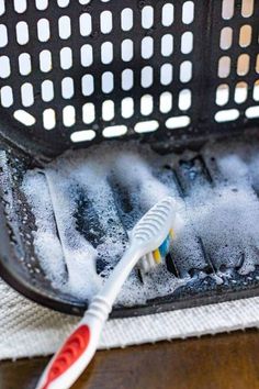 an electric toothbrush is sitting on the floor in front of a wire basket filled with water