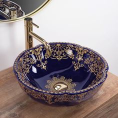 a blue bowl sink sitting on top of a wooden counter next to a bathroom mirror