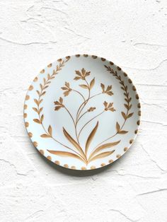 a white and gold plate sitting on top of a wall