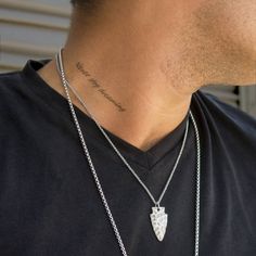 a man with a tattoo on his neck wearing a black t - shirt and silver necklace