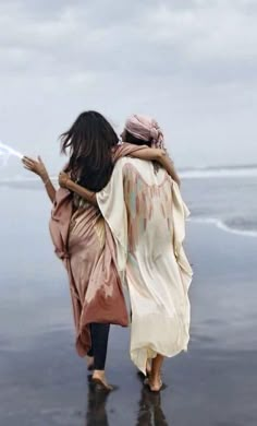 two women walking on the beach with their arms around each other