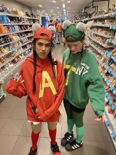 two girls in costumes standing next to each other at a grocery store with shelves full of food