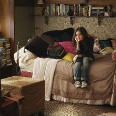 a woman sitting on top of a bed next to a book shelf filled with books