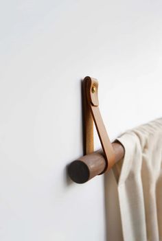 a close up of a towel rack on a white wall with a curtain in the background