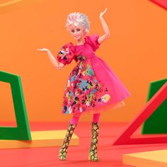 a barbie doll is standing in front of an orange and green background with colorful letters