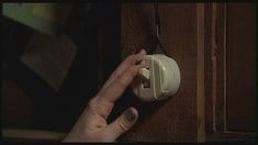 a woman's hand is pressing the light switch button on a wooden cabinet door