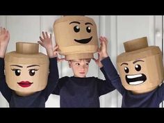 three children wearing paper bags with faces on their heads and hands above their heads, one boy is covering his eyes