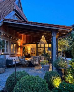 an outdoor living area with patio furniture and string lights on the roof is lit up at night