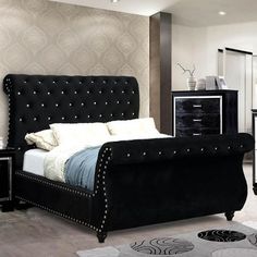 a black and white bedroom with an upholstered bed, nightstands, mirror and drawers