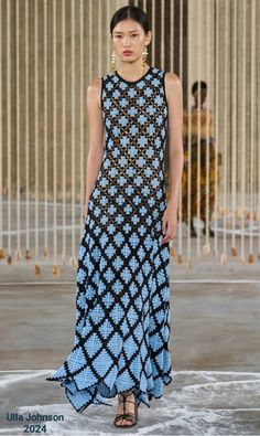 a model walks the runway in a blue and black dress with an intricate pattern on it