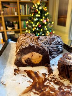 there is a chocolate cake on the table with a christmas tree in the back ground