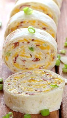 several rolls with cheese and green onions on a cutting board next to each other, ready to be eaten