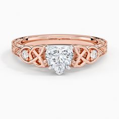 a rose gold engagement ring with a heart shaped diamond in the center and side stones