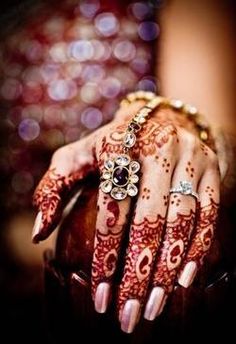 a woman's hands with henna and jewelry