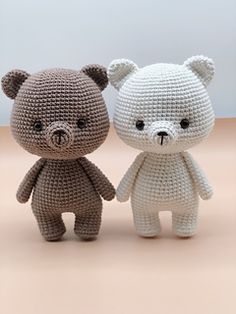 two crocheted teddy bears sitting next to each other on top of a table