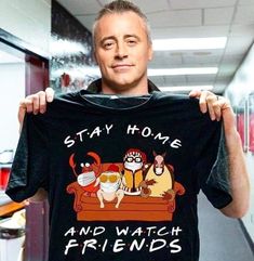 a man holding up a t - shirt with the words stay home and watch friends on it