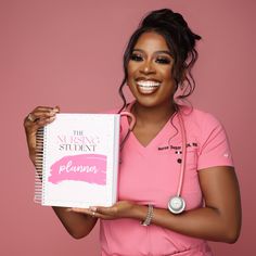 a woman in pink shirt holding up a notebook with writing on it and stethoscope