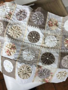 a quilted table cloth with many different designs and colors on it, sitting on top of a wooden floor