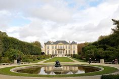 a large building with a fountain in front of it and lots of trees around it