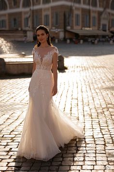 a woman in a wedding dress is walking down the street with her hand on her hip