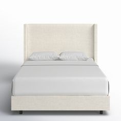 a bed with white linens and pillows on it's headboard is shown