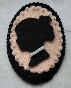 a black and white brooch with pearls on it's side, in the shape of a woman's head