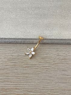 a gold flower brooch sitting on top of a wooden floor next to a wall