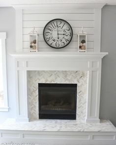 a white fireplace with a clock above it and candles on the mantle in front of it